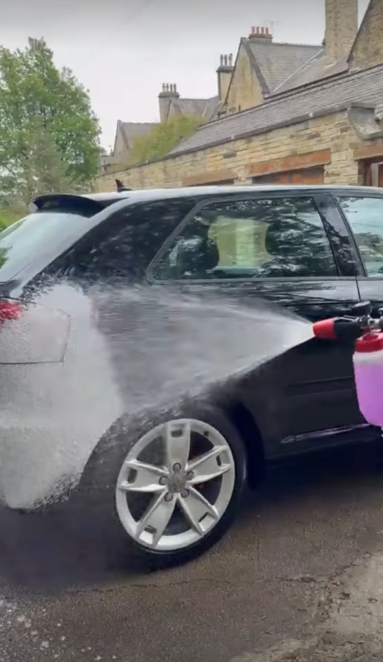 Thick white pre-wash snow foam being applied to a black car using the JN Supplies heavy duty snow foam lance cannon.