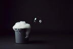 Gray bucket filled with white foam on a black background